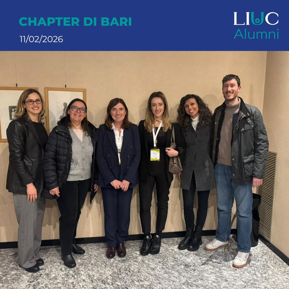 Sei persone in piedi in posa davanti a una parete beige con dei quadri; in alto una fascia blu con la scritta «CHAPTER DI BARI 11/02/2026» e il logo «LIUC Alumni».